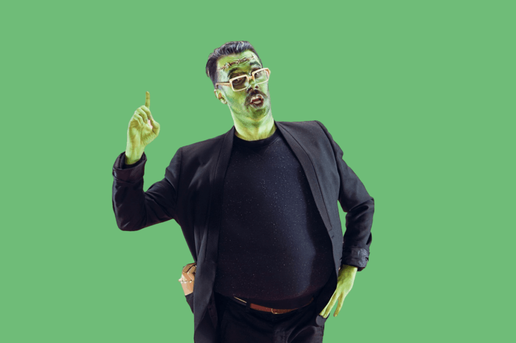 Ein Mann mit grüner Haut, weißer Brille und schwarzem Anzug gestikuliert mit einer erhobenen Hand, als wolle er auf etwas hinweisen, vor einem kräftigen grünen Hintergrund - die perfekte Inspiration für einzigartige Halloween-Kostüme.