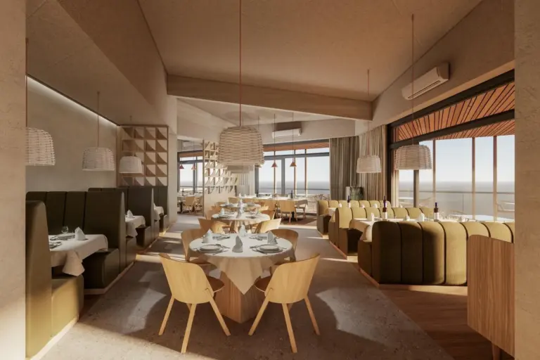 Ein modernes Restaurant mit Holztischen und -stühlen, Hängelampen, grünen Sitznischen, großen Fenstern und Blick auf das Meer draußen. Die Tische sind mit Tellern, Gläsern und Utensilien gedeckt. Die Atmosphäre ist hell und luftig.