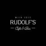 Schwarzer Hintergrund mit weißem Text, der lautet: WIEN 1010 Rudolf's Cafe & Bar in einer stilvollen Schriftart. Dünne Linien trennen Rudolf's Cafe & Bar vom Rest des Textes.
